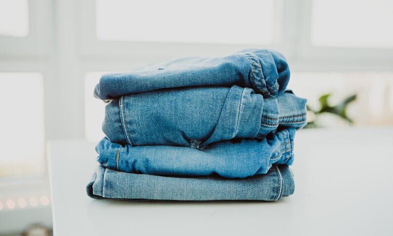 Ein Stapel blauer Jeans liegt auf einem Tisch  | ©  Getty Images / Carol Yepes
