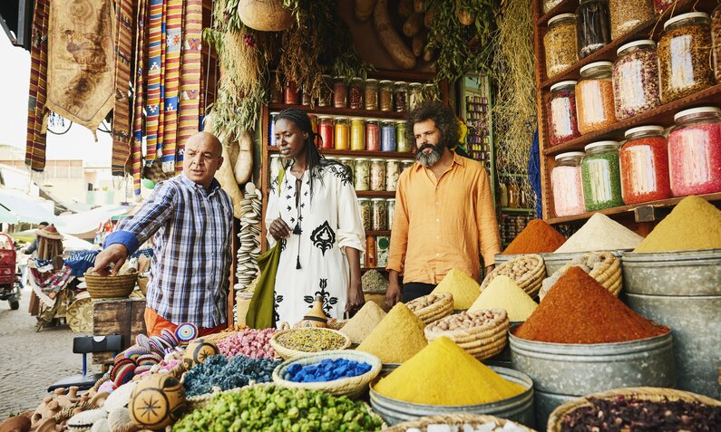 Händler stehen an einem bunten Gewürzstand in einer Gasse Marrakeschs | ©  Getty Images / Thomas Barwick