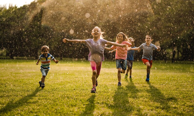 Kinder laufen durch den Sommerregen  | ©  Getty Images / StockPlanets