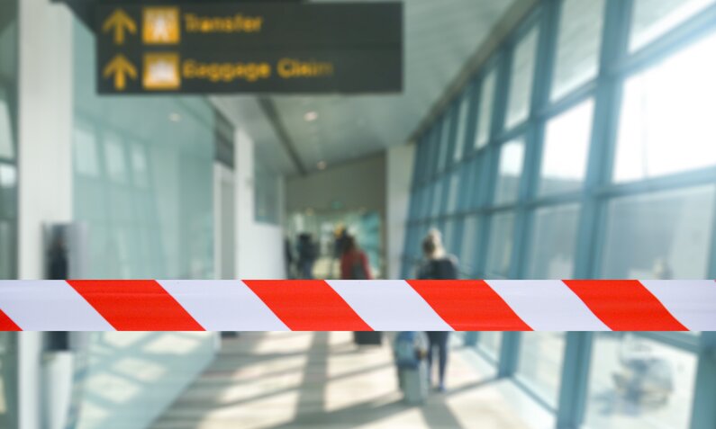 Absperrband an einem Flughafen, Im Hintergrund unscharf ein Schild  | ©  Getty Images / SPmemory