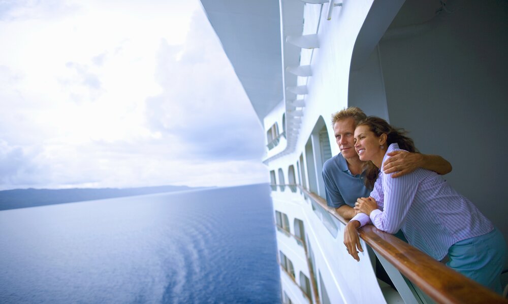 Pärchen steht Arm in Arm an der Reling eines Kreuzfahrschiffes | ©  Getty Images / David Sacks