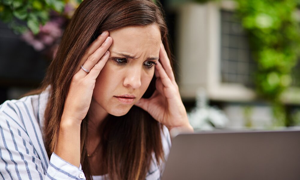 Junge Frau bllickt genervt auf ihren Computer-Bildschirm | © Getty Images/Dean Mitchell