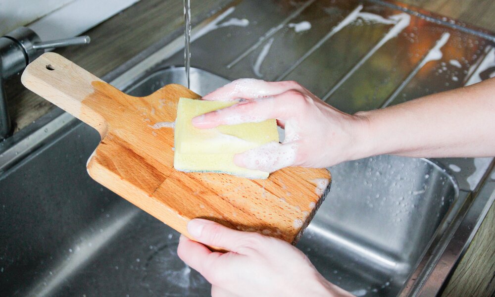 Jemand wäscht ein Holzschneidebrett ab  | ©  Getty Images / Kinga Krzeminska