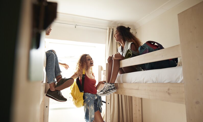 3 junge Frauen reden und lachen in einem Hostelzimmer | ©  Getty Images / Klaus Vedfelt