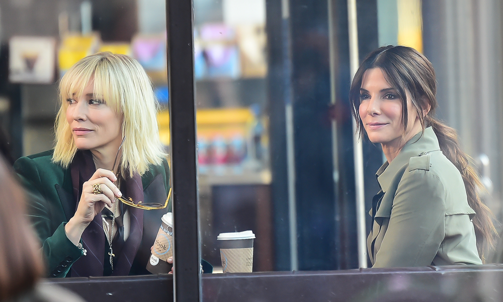 Cate Blanchett und Sandra Bullock sitzen lächelnd im Cafe bei den Dreharbeiten zum Film "Ocean's 8" | © Getty Images/Raymond Hall
