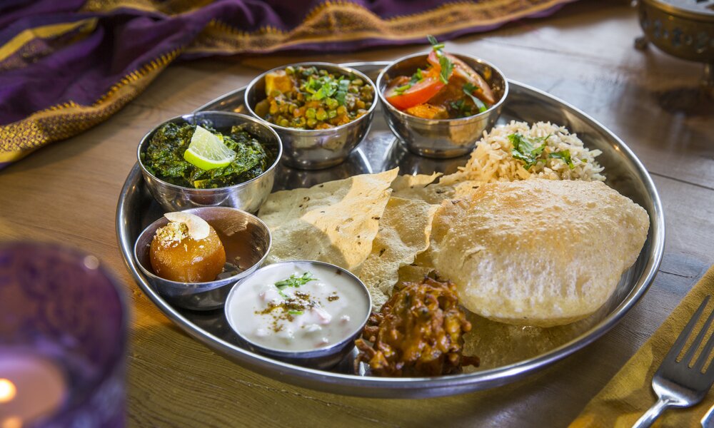 Ein Thali-Teller mit vielen kleinen Portionen und Naan-Brot in der Mitte | ©  Getty Images / RUSS ROHDE