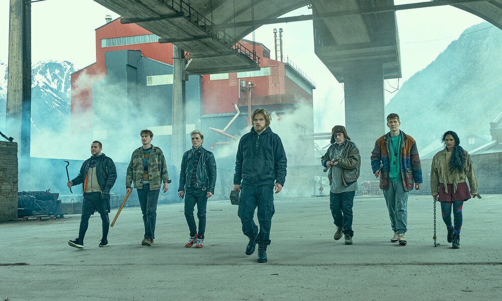 Benjamin Helstad als Harry, Vebjørn Enger als Jens, Jonas Strand Gravli als Laurits, David Stakston als Magne, Bjørn Sundqvist als Wotan, Ruben Rosbach als Kiwi und Danu Suntharasigamany als Iman gehen bewaffnete eine Straße entlang in einer Szene der Netflix Serie "Ragnarök" Ragnarok | © Netfli/Christian Geisnaes