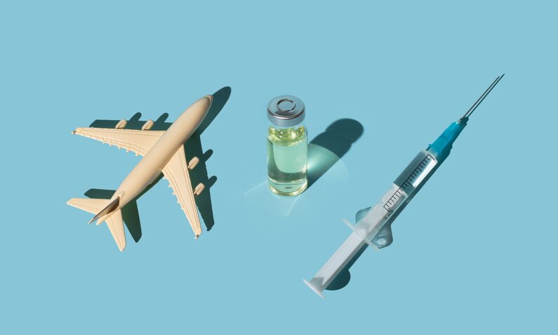 Ein Modellflugzeug, eine Phiole mit Impf-Flüssigkeit und eine Spritze | ©  Getty Images / Tanja Ivanova