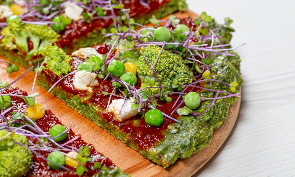 Grüne Pizza in Nahaufnahme, belegt mit Mozarella, Brokkoli und Erbsen. | © Getty Images / Anatolie Voiculet / 500px