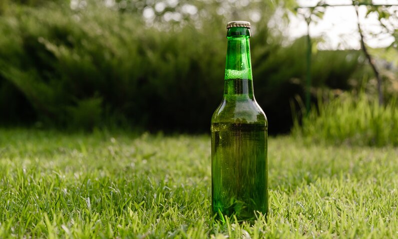 Bierflache steht auf einer Rasenfläche | ©  Getty Images / inside-studio