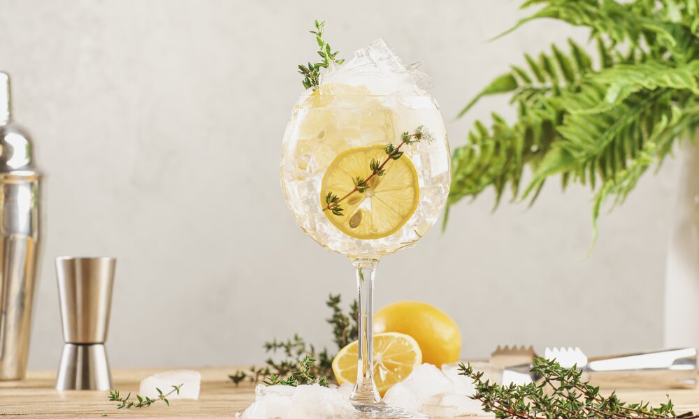 Ein Glas gefüllt mit einem Drink, dazu etwas frischer Thymian und Zitrone. | © Getty Images / 5PH / 500px