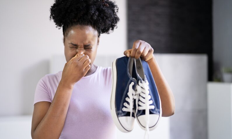 Frau hält sich die Nase zu und steckt Sneaker von sich weg  | ©  Getty Images / AndreyPopov