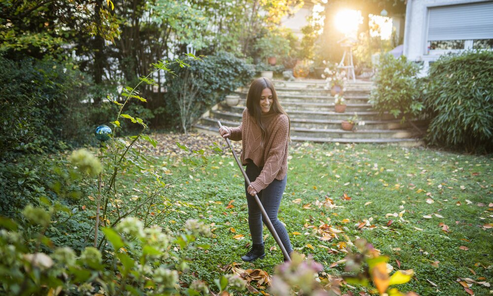 Frau recht Laub im Garten  | © Getty Images / Westend61