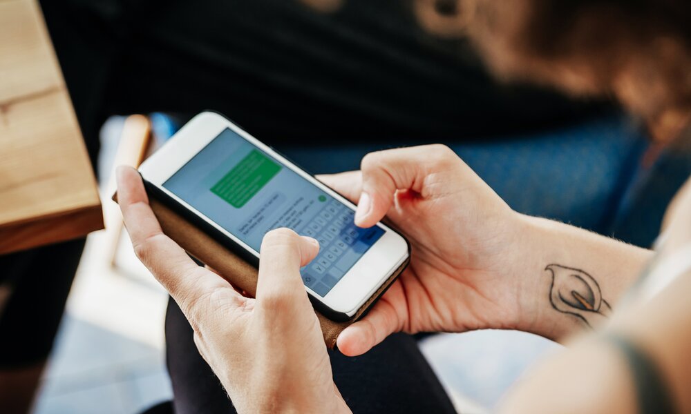 Frau tippt auf dem Smartphone eine Nachricht in den WhatsApp-Messengerdienst ein. | © Getty Images/Tom Werner