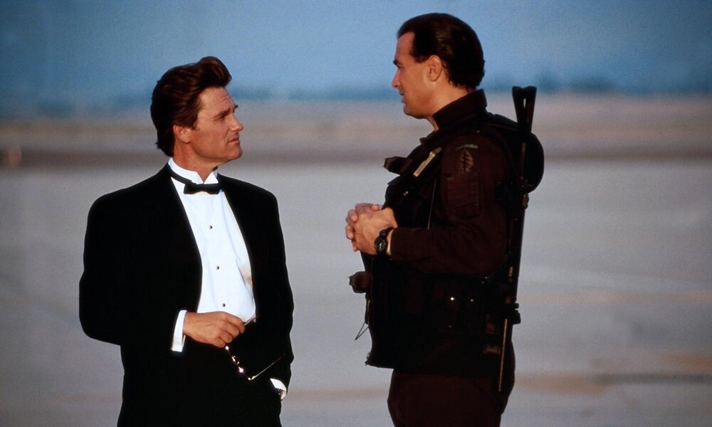 Kurt Russel im Smoking und Steven Seagal in militärischer Ausrüstung stehen sich auf einem Flugfeld gegenüber und sprechen miteinander in einer Szene aus dem Kinofilm "Einsame Entscheidung" | © ddp images