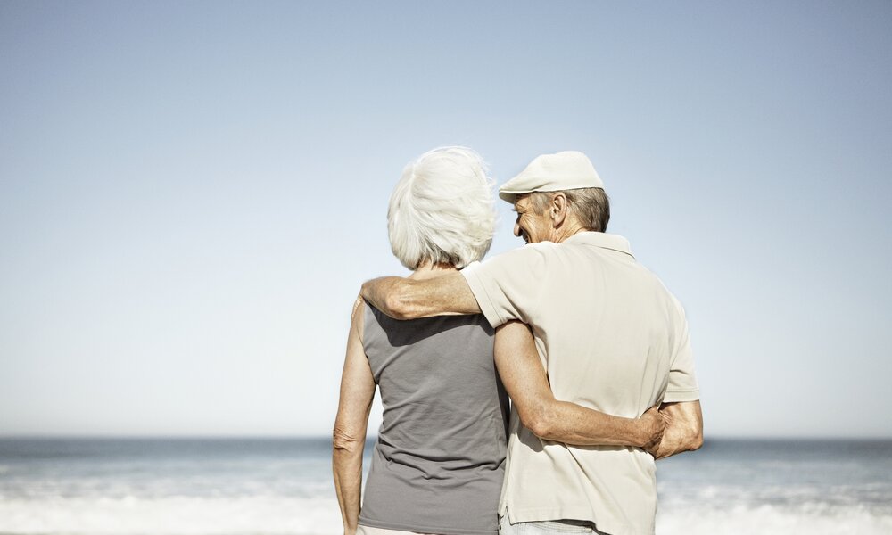  Seniorenpärchen steht Arm in Arm am Strand | ©  Getty Images / Roger Wright