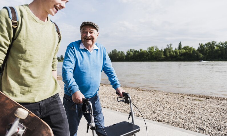 Älterer Mann mit Rollator geht mit jüngerem Mann spazieren | ©  Getty Images / Westend61