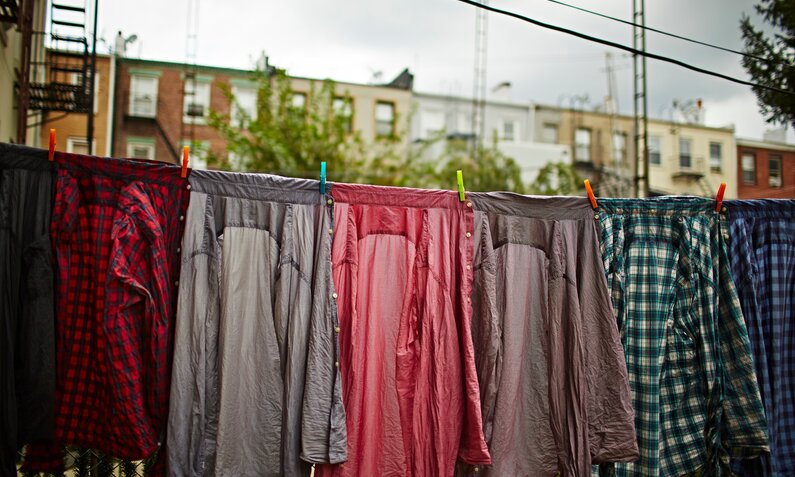 Wäsche hängt über einer Balkon-Reling, im Hintergrund grauer Himmel  | ©  Getty Images / Cultura/JPM