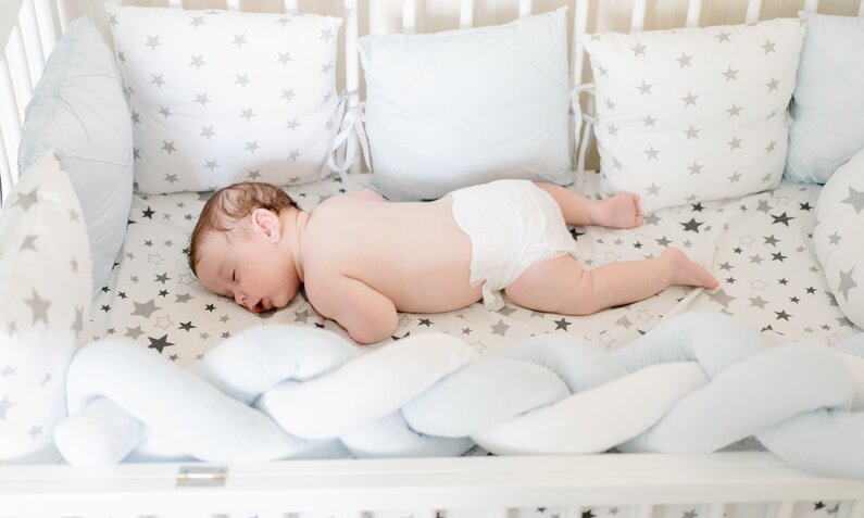 Baby liegt auf dem Bauch im Babybett. | © Getty Images / Switlana Sonyashna