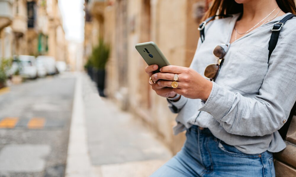 Frau im Urlaub an ihrem Handy | ©  Getty Images / urbazon