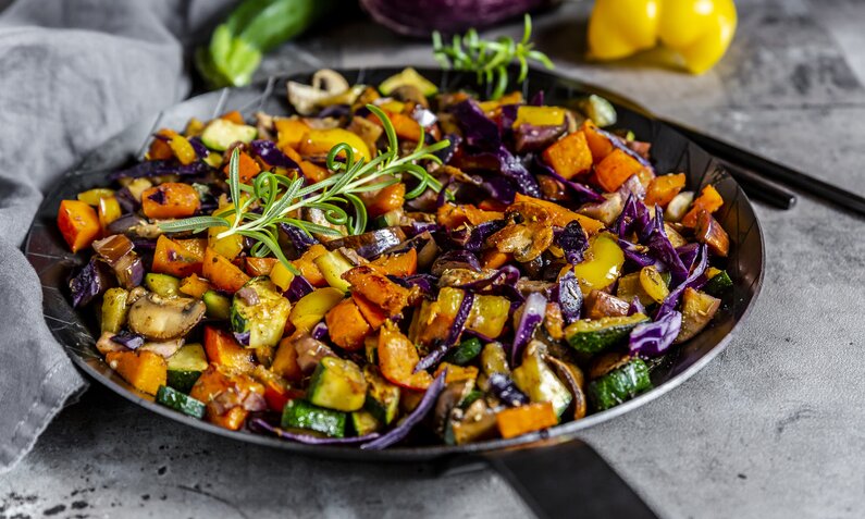 Ein buntes Pfannengericht mit Gemüse und Kürbis. Garniert mit einem Rosmarinzweig. | © Getty Images / lacaosa