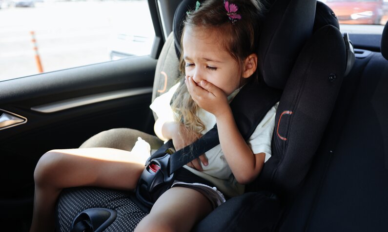 Kleines Mädchen sitzt im Auto und hält sich die Hand vor den Mund | ©  Getty Images / ozgurcankaya
