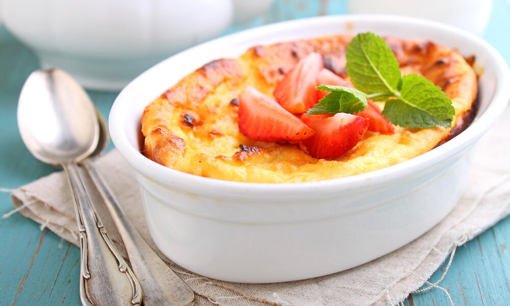 Auflaufform mit Quarkdessert, goldbraun, belegt mit frischen Beeren. | © Getty Images / alely