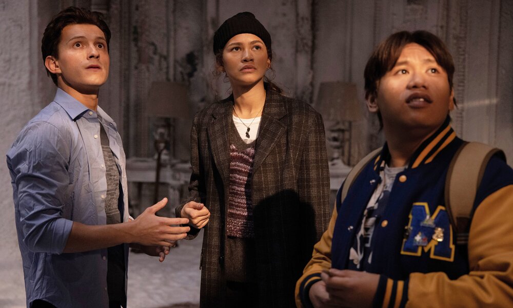 Tom Holland, Zendaya und  Jacob Batalon stehen in einer Szene aus dem Kinofilm "Spider-Man: No Way Home" in einem Raum und blicken nach oben. | ©  ddp images/LMKMEDIA Ltd.