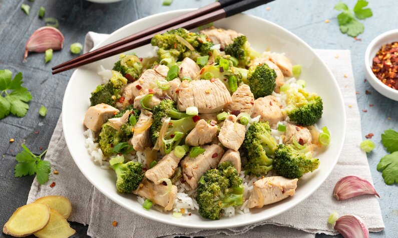 Auf einem weißen Teller sind frischer Brokkoli und knuspriges Hähnchenfleisch angerichtet. | © Getty Images / DronG