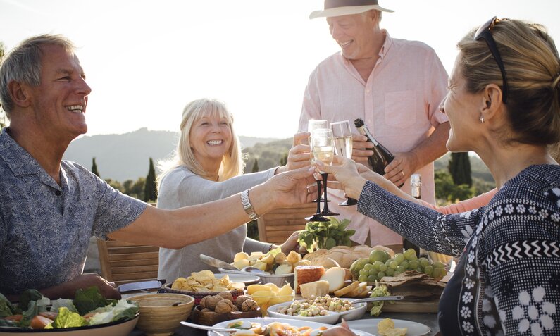 Senioren stoßen mit Wein auf ihr Essen an  | ©  Getty Images / SolStock