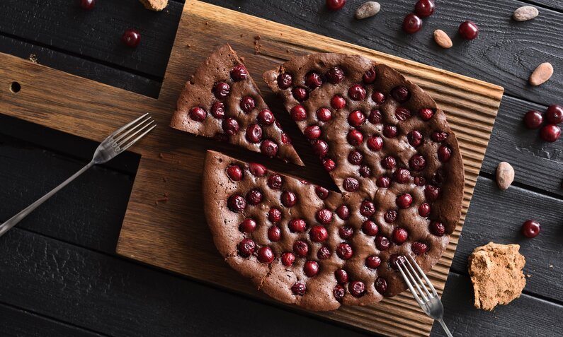 Schoko-Kirsch-Kuchen auf einem rustikalen Brett angerichtet. | © Getty Images / AlexeyBorodin