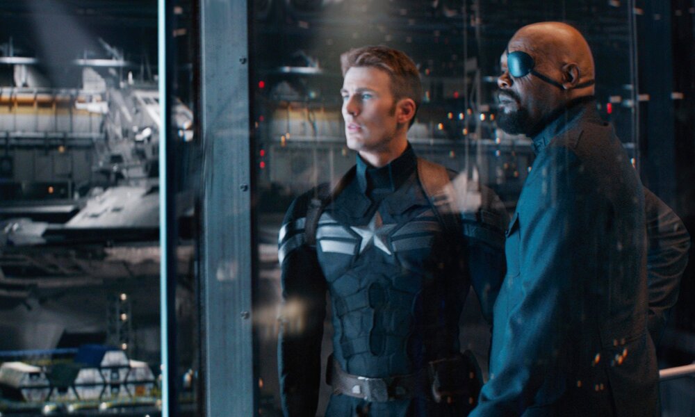 Chris Evans als Captain America und Samuel L. Jackson als Nick Fury stehen nebeneinander bei Nacht vor einer Glasscheibe in einer Szene aus dem Kinofilm "The Return of The First Avenger" | © ddp images/Walt Disney Studios M