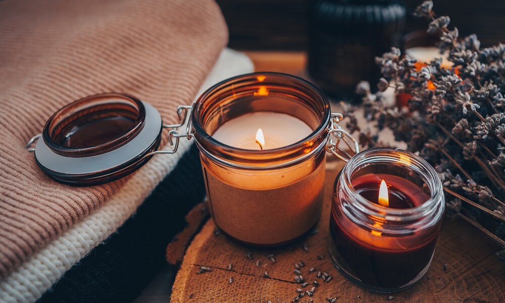 Amazon | © Duftkerze im Glas auf einer Decke vor weihnachtlichem Hintergrund