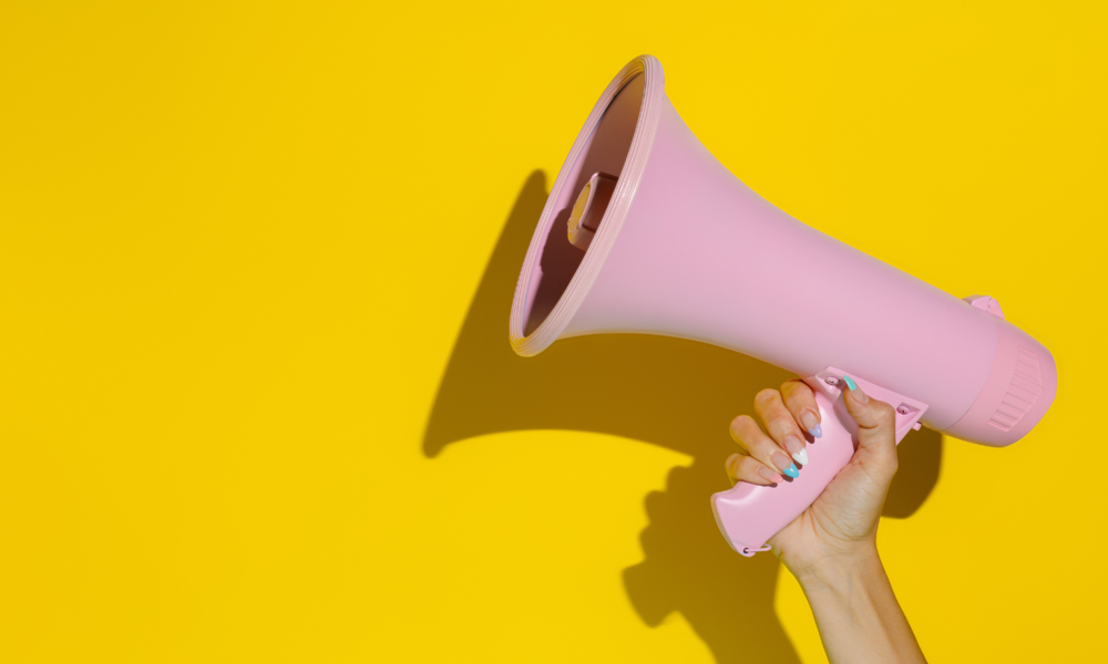 Frau hält Megafon in die Luft | ©  Shutterstock / Gligoric