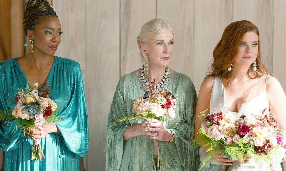 Heather Headley als Helen, Caroline Lagerfelt als Paula und JoAnna Garcia Swisher als Maddie stehen in einer Szene der Netflix-Serie "Süße Magnolien" in festlichen Kleidern und mit Blumen in der Hand nebeneinander. | © Netflix
