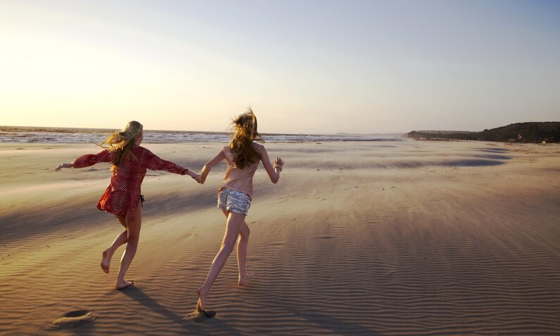 Zwei Mädchen laufen am Strand | ©  Getty Images / Karan Kapoor