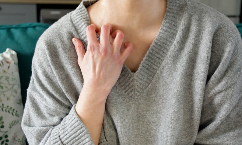 Frau kratzt sich am Hals | ©  Getty Images / Kinga Krzeminska