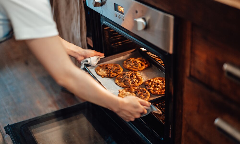 Frau holt Kekse aus dem Backofen | ©  Getty Images / Oscar Wong