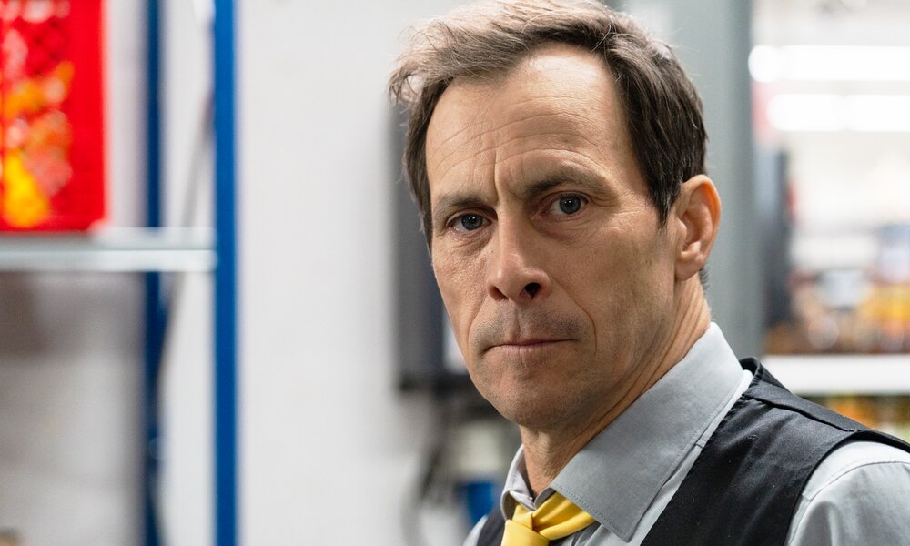 Nachaufnahme von Marc Hoseman als Marktleiter in einer Szene aus der Prime Video Serie "Die Discounter", in der er im Büroraum von "Kolinski" steht | © Prime Video/Johannes Fielers/Pyjama Pictures