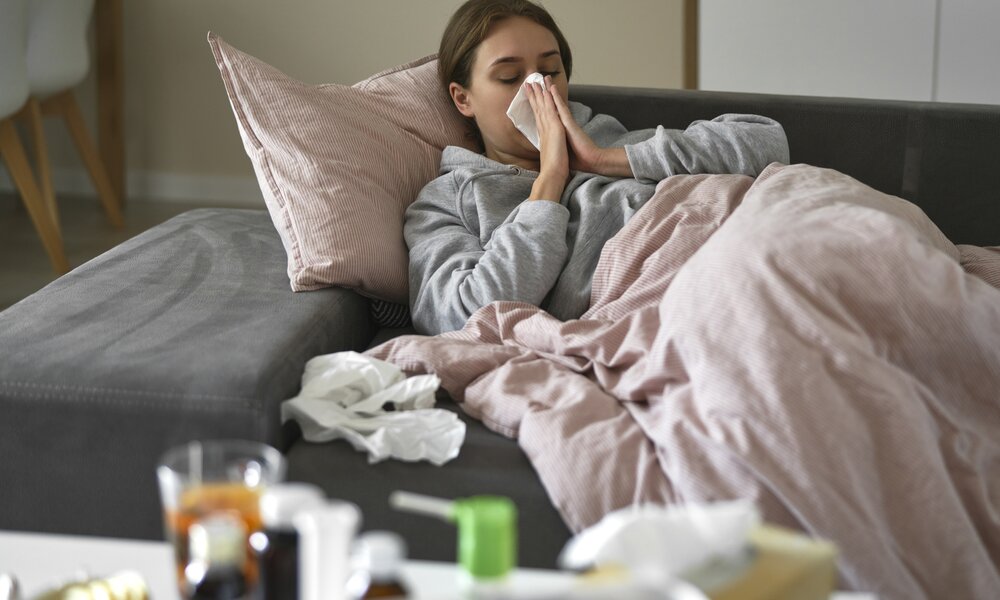 Frau liegt Krank auf der Couch und putzt sich die Nase | ©  Getty Images / gpointstudio