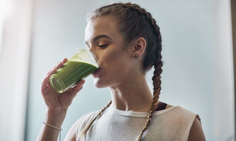 Junge Frau trinkt einen grünen Smoothie. | © Getty Images / Matt Lincoln