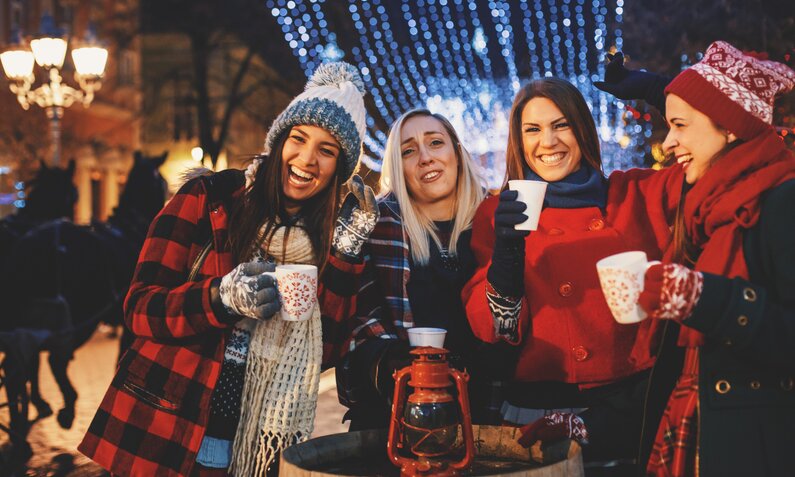 Freunde auf dem Weihnachtsmarkt trinken Glühwein | ©  Getty Images / fotostorm