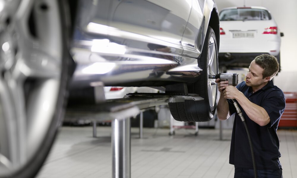 Mann wechselt dem Auto die Reifen | ©  Getty Images / Adam Gault
