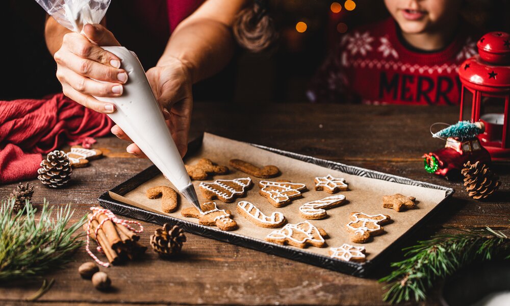 Frau verziert gebackene Kekse mit Zuckerguss. | © Getty Images / alvarez