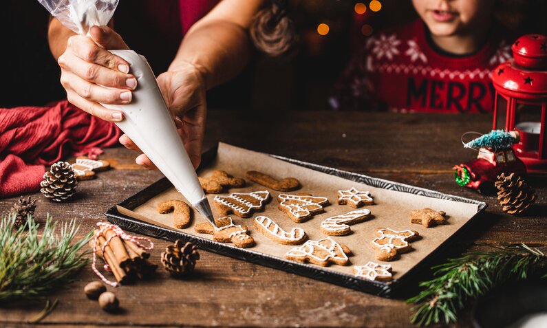 Frau verziert gebackene Kekse mit Zuckerguss. | © Getty Images / alvarez