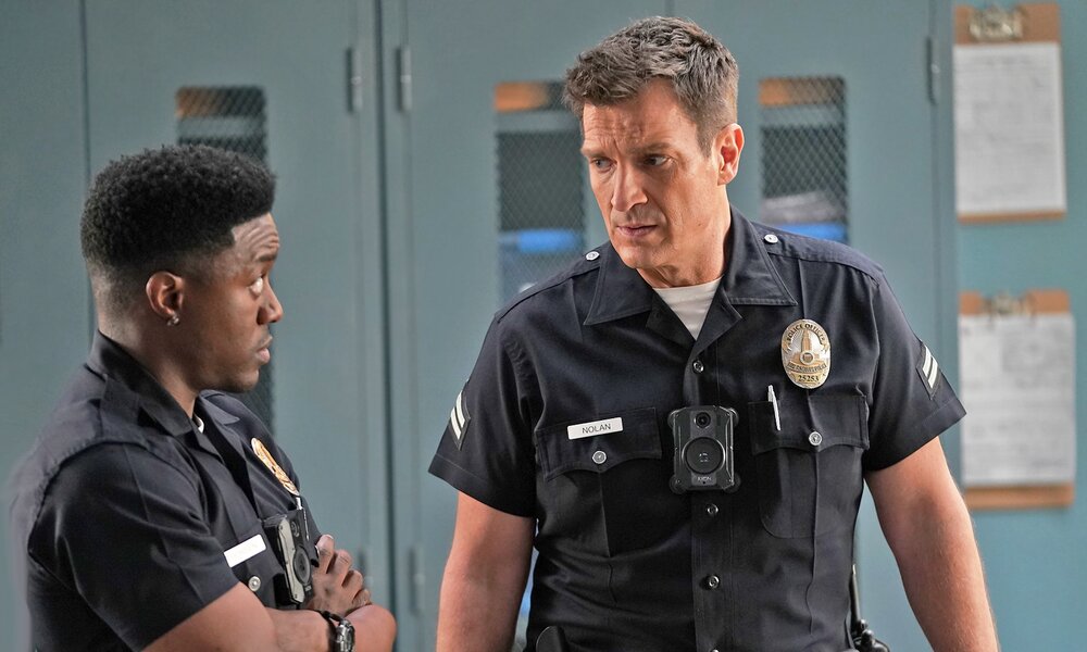 Tru Valentina und Nathan Fillion stehen sich in einer Szene aus der Serie "The Rookie" in ihren dunkelblauen-Copuniformen im Gespräch gegenüber | © Getty Images/Gilles Mingasson