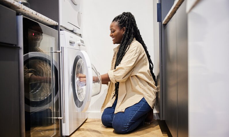 Frau befüllt Waschmaschine mit Wäsche. | © Getty Images / Goodboy Picture Company