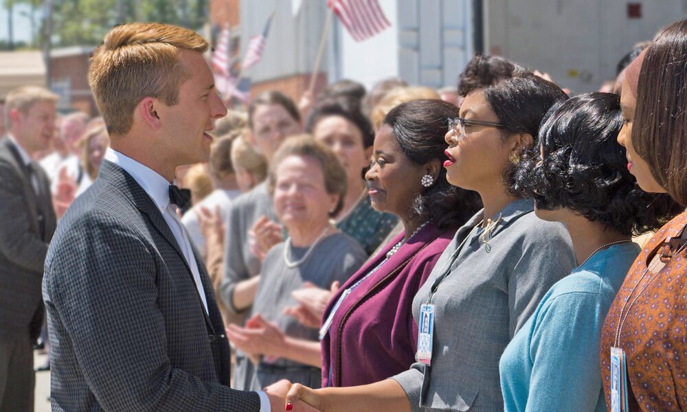 Glen Powell schüttelt die Hand von Taraji P. Henson, die neben Octavia Spencer und Janaelle Monáe steht in einer Szene aus dem Kinofilm "Hidden Figures" | © ddp images/ZUMA Wire