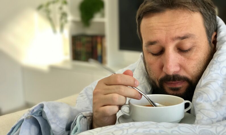 Mann ist krank und isst Suppe | ©  Getty Images / Jasmin Merdan