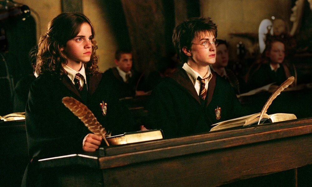 Emma Watson und Daniel Radcliffe sitzen in einer Szene aus dem Kinofilm "Harry Potter und der gefangene von Askaban" in Schuluniformen im Klassenzimmer nebeninander  | © ddp images
